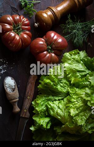Bio frische Tomaten und Salat aus dem Gemüsegarten auf einem alten Holztisch, das Konzept der Diät und gesunde Ernährung, rustikaler Stil, Draufsicht Stockfoto