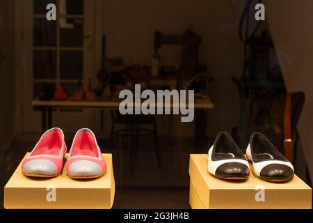 Zwei Paar Schuhe liegen nachts auf Schaupodesten in einer Schaufensterdisplays einer Schuhmacherwerkstatt. Stockfoto