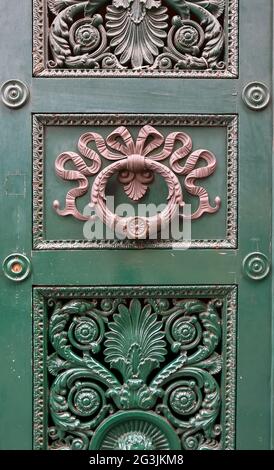 Nahaufnahme der grünen Tür eines antiken Gebäudes mit einem bogenförmigen Klopfer und geschnitztem Holz, Genua, Ligurien, Italien Stockfoto