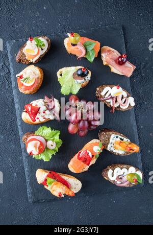 Eine Auswahl an klassischen spanischen und italienischen Sandwiches - Tapas und Bruschetta - ein traditionelles Gericht der mediterranen Küche. Garnelen, Tintenfisch, Lachs, Käse Stockfoto