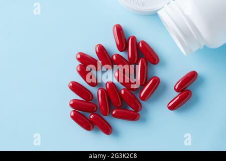 Rote Kapseln Pille auf blauem Hintergrund mit Schatten verteilt. Globales Gesundheitskonzept. Antibiotikaresistenz. Antimikrobielle Kapseln. Pharmac Stockfoto