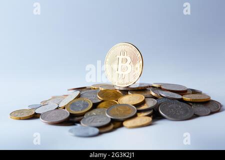 Goldene und glänzende Bitcoin-Münzen auf verschiedenen Weltwährungen, die eine Auswahl an verschiedenen Zahlungs- und Anlageoptionen darstellen. Stockfoto