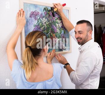 Der Mann hängt das Bild zusammen mit seiner Frau an die Wand Stockfoto