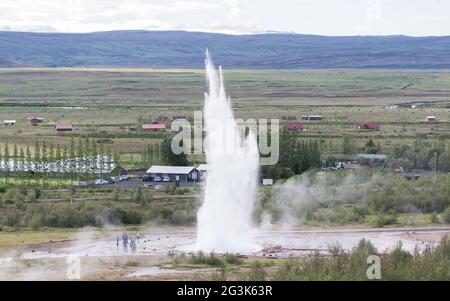 Beeindruckende Eruption des größten aktiven Geysir, Strokkur, mit Touristen warten herum, Golden Circle Stockfoto