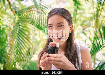 Spam musubi Reis Ball Sandwich Asiatische Frau Tourist essen japanische Snack Essen typisch für hawaii-Markt in Hawaii. Stockfoto