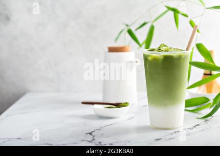 Kalter Matcha Latte in einem hohen Glas auf Marmor Stockfoto