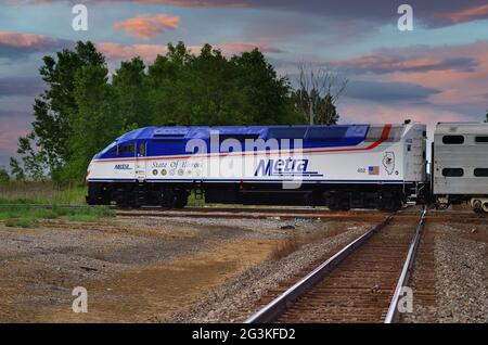 Bartlett, Illinois, USA. Ein Metra-Pendlerzug, der auf seiner Reise nach Chicago durch eine Kreuzung mit einer anderen Eisenbahn fährt. Stockfoto