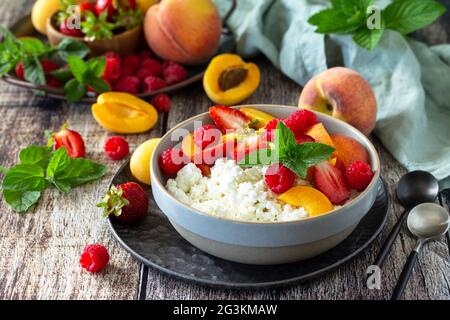 Rustikales Sommerfrühstück oder Dessert. Quark oder Quark mit frischen Sommerfrüchten und Beeren auf einem Holztisch. Stockfoto
