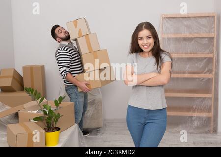 Attraktives junges Paar bewegt lächelnd stehen unter Kartons. Stockfoto