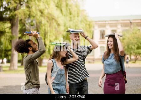 Junge College-Studenten zu Fuß mit Bücher auf ihren Köpfen. Stockfoto