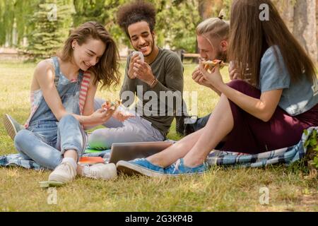 Studenten der Universität Essen Pizza während des Studiums auf dem Rasen. Stockfoto