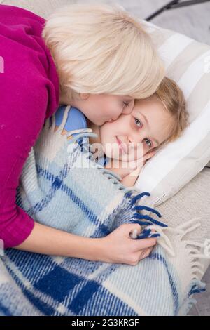 Draufsicht auf die Mutter, die ihre kleine kranke Tochter küsst. Stockfoto