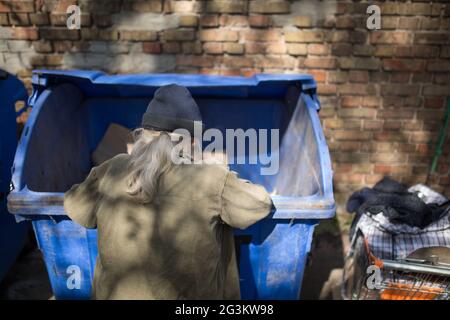 Obdachlose alte Mann Graben im Papierkorb. Stockfoto