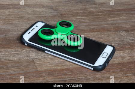 Kinderspielzeug; Smartphone mit einem Spinner auf der Oberseite Stockfoto
