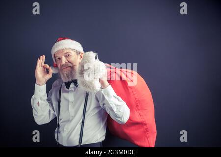 Weihnachtsmann hält rote Tasche mit Geschenken. Stockfoto