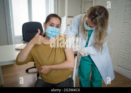 Ärztin oder Krankenschwester, die junge Frau in der Klinik impft. Männlicher Patient, der gegen Coronavirus geimpft wird, erhält einen Covid-Impfstoff intramuskulär in Stockfoto