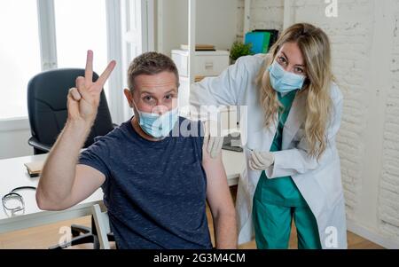 Ärztin oder Krankenschwester, die einen jungen Mann in der Klinik impft. Männlicher Patient, der gegen das Coronavirus geimpft wird, erhält einen Covid-Impfstoff, intramuskulär Inje Stockfoto