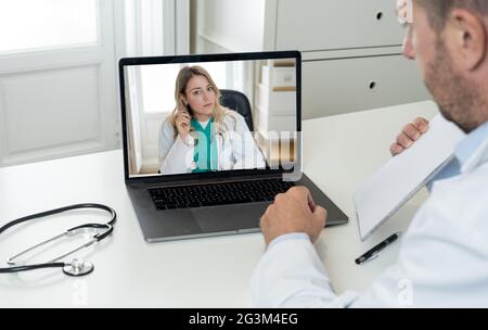 COVID-19 Online Gesundheitswesen. Ärztin Fachärztin für virtuelle medizinische Beratung mit Teamärztin in Videokonferenz-Meeting. Telemedizin und m Stockfoto