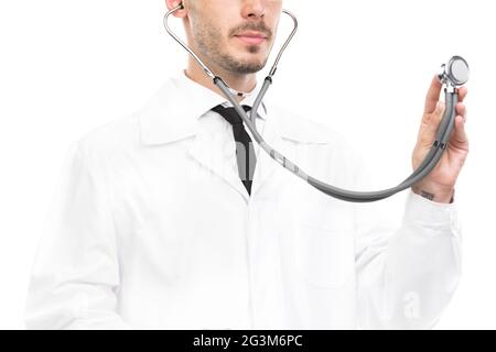 Porträt eines hübschen jungen kaukasischen Arztes mit weißem Mantel und Brille, der mit Stethoskop Herzschlag und Atem der Patienten untersucht Stockfoto