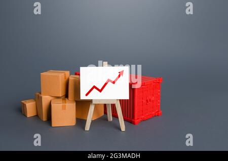 Boxen und Container in der Nähe der Staffelei mit einer positiven Grafik. Wachstum des Gütertransportvolumens, Erholung des Welthandels. Wirtschaftliche Bindungen. Gebühren A Stockfoto