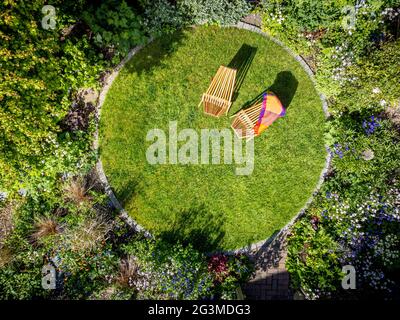 Luftbild des Hausgartens mit kreisförmigem Rasen und zwei Holzdeckstühlen Stockfoto