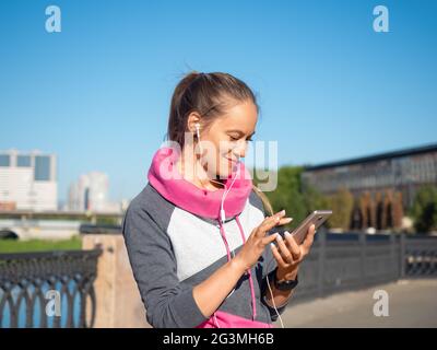 Junge Frau mit einem Smartphone. Sie wählt Joggingmusik. Stockfoto