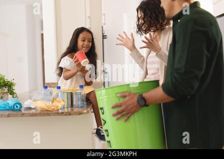 Glückliche hispanische Tochter und Eltern, die Müll für das Recycling in der Küche sortieren Stockfoto