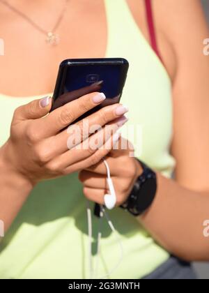 Weibliche Hände mit Smartphone-Nahaufnahme. Sie wählt Musik für ihren morgendlichen Lauf. Stockfoto
