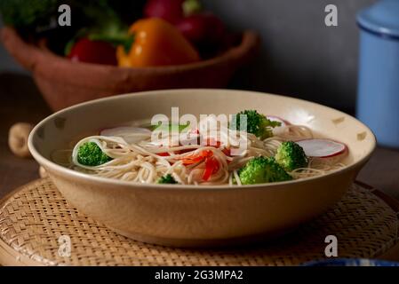 Schmackhaftes Fleisch Brühe mit Nudeln, Brokkoli und Petersilie in eine Schüssel geben. Stockfoto