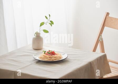 Handgemachte Pasta mit Ragout Soße auf Platte auf Vintage White Tisch mit Sieb und Blumen Stockfoto