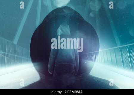 Eine Doppelbelichtung einer geheimnisvollen Kapuzenfigur, die auf einem Pfad auf einer Brücke steht. Silhouetten gegen helle Lichter in der Nacht. Mit einem Neon, Retro, scien Stockfoto