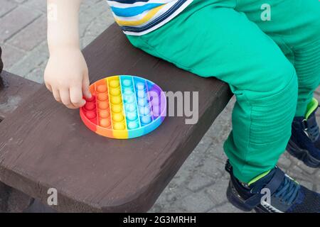 Spielzeug Antistress bunt Pop it und ein kleines Kind Nahaufnahme. Stockfoto