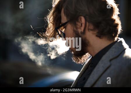 Ein Mann mit langen Haaren raucht außerhalb Stockfoto