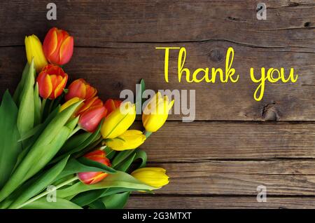Dankesnachricht, bunte Tulpen auf Holzhintergrund. Frühlingsblumen Hintergrund mit blühenden Tulpen, Mockup Vorlage, Grußkarte Feier. Stockfoto