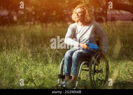 Frau im Rollstuhl wirft Frisbee Stockfoto