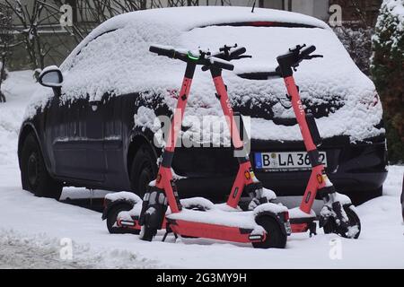 '16.02.2021, Berlin, , Deutschland - E-Scooter des Anbieters Voiscalleroters stehen schneebedeckt auf einer Straße. 00S210216D982CAROEX.JPG [MODELLVERSION: NEIN, Stockfoto