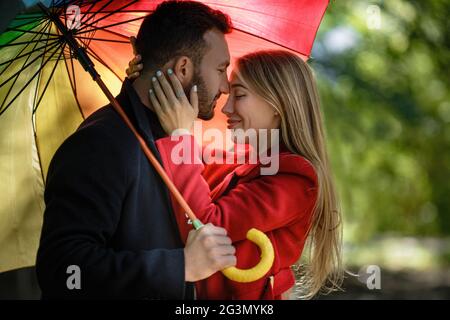 Junge Menschen wandern im Park unter bunten Regenschirm Stockfoto