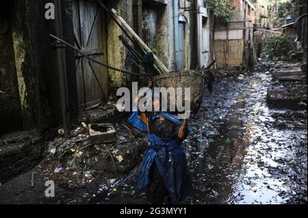 '19.02.2014, Yangon, , Myanmar - EINE Kanalisationsreinigerin in einfacher Schutzkleidung aus zerrissenen Plastiksäcken reinigt die verstopfte offene Kanalisation der Stadt sy Stockfoto