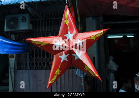 '31.10.2015, Yangon, , Myanmar - EIN roter Pappstern mit dem Logo der NLD (National League for Democracy) Partei hängt an einem Straßenstand in der Stockfoto
