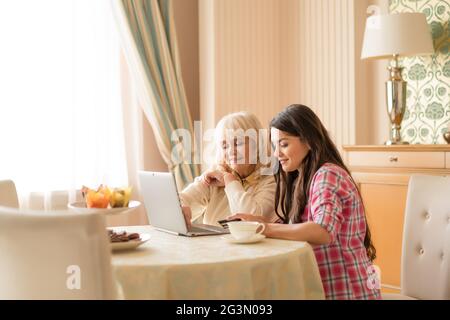 Charmante Mutter und Tochter einkaufen online mit Kreditkarte Stockfoto