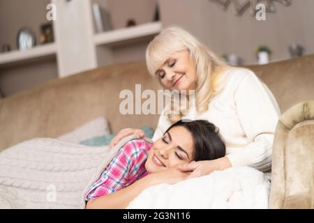 Charmantes Mädchen liegt auf den Knien der Mutter auf dem Sofa Stockfoto