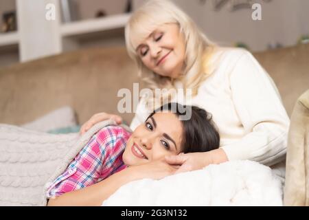 Charmantes Mädchen liegt auf den Knien der Mutter auf dem Sofa Stockfoto