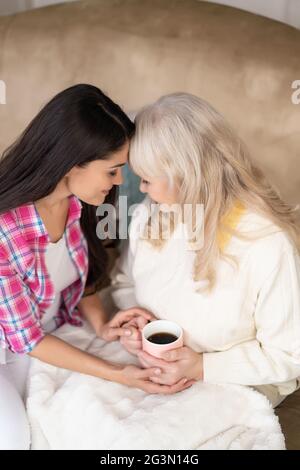 Ältere Mutter und hübsche Tochter berühren die Stirn. Stockfoto