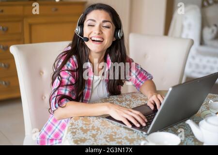 Die schöne Frau arbeitet mit Headsets an ihrem Laptop Stockfoto