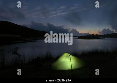 Outdoor-Abenteuer im Zelt in der Natur Siziliens, wildes Camp an einem See in der Abenddämmerung in den Nebrodi-Bergen Stockfoto