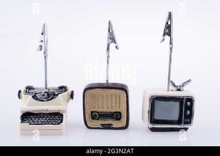 Retro-Modell mit winzigen Fernsehern, Radio und Schreibmaschine auf weißem Hintergrund Stockfoto