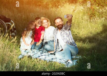 Glückliche Familie selfie auf dem Picknick im Park. Paraplegic Stockfoto