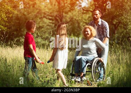 Lächelnde Kinder spielen mit ihren behinderten Jungen Mutter Stockfoto