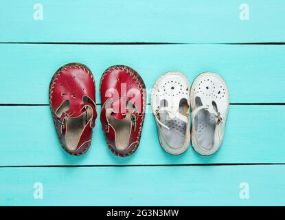 Zwei Paar Leder-Kindersandalen auf blauem Holzhintergrund. Draufsicht Stockfoto