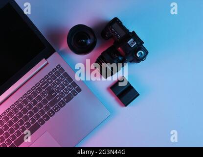 Professioneller Fotograf für die Ausrüstung. Laptop, Kamera, Objektive. Neonlicht. Draufsicht Stockfoto